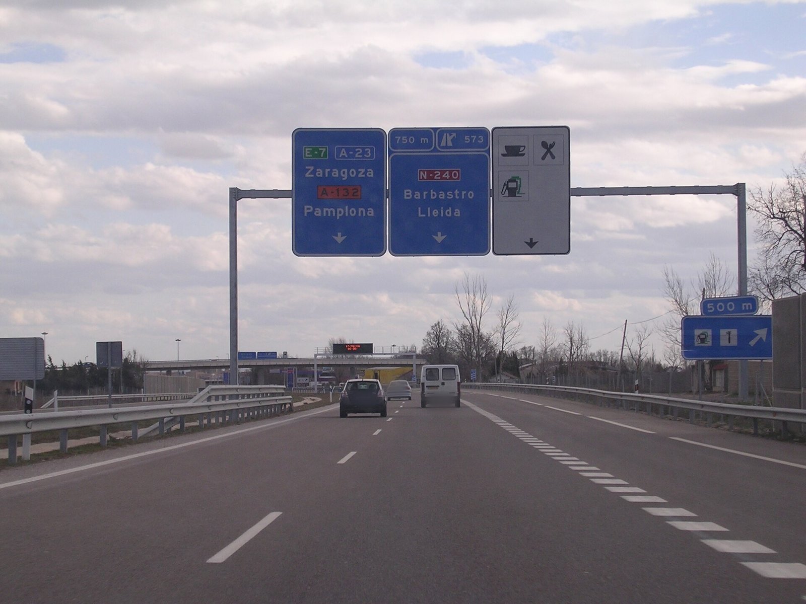 Autovía con un pórtico de señales de salida por delante, vista desde el coche