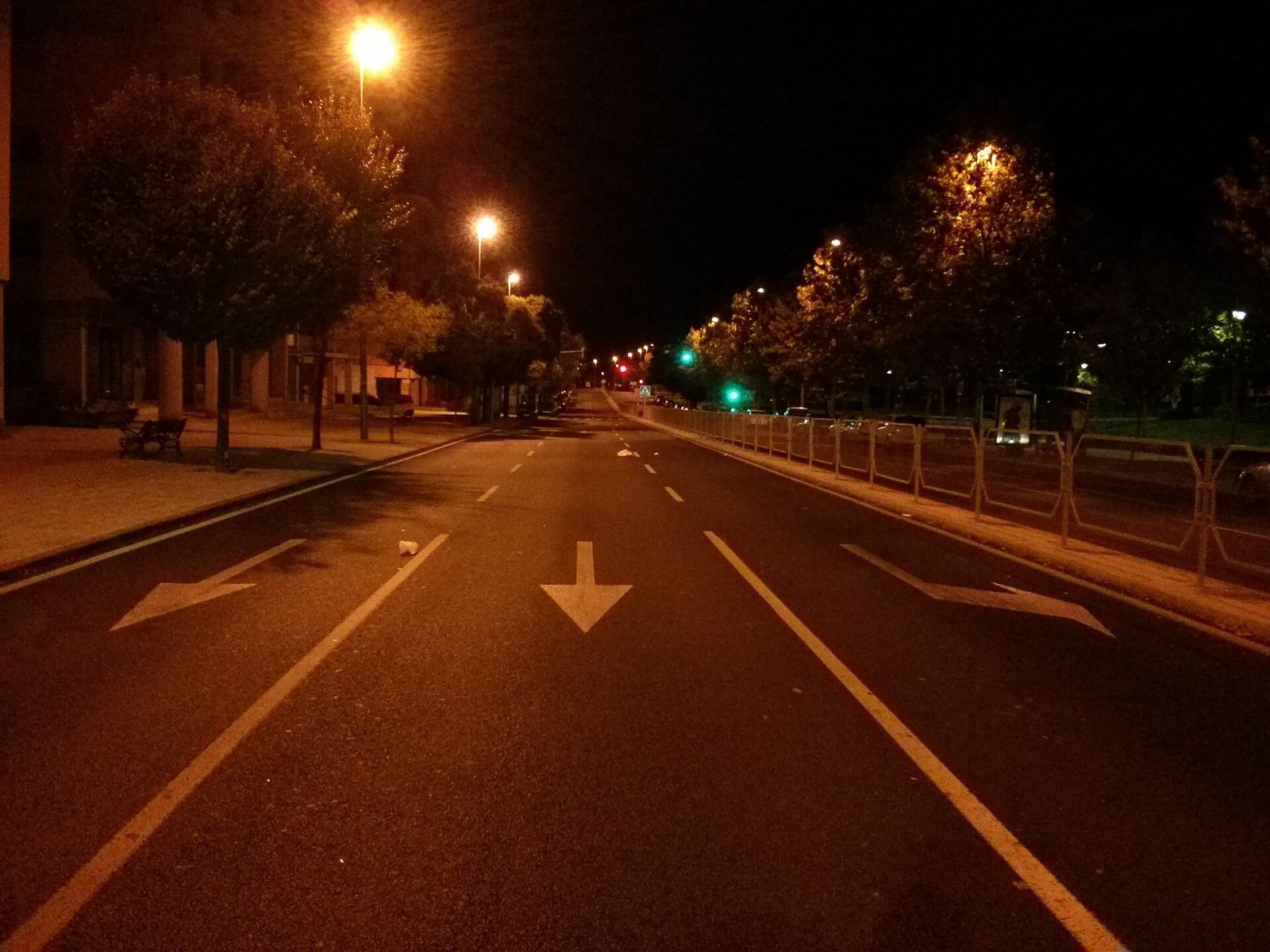 Avenida urbana iluminada con farolas y sin vehículos, de noche