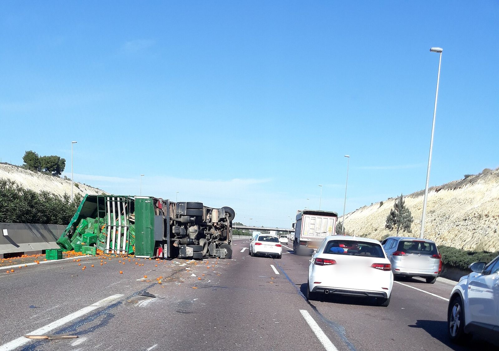 Camión volcado en una autovía con tráfico retenido, visto desde un coche