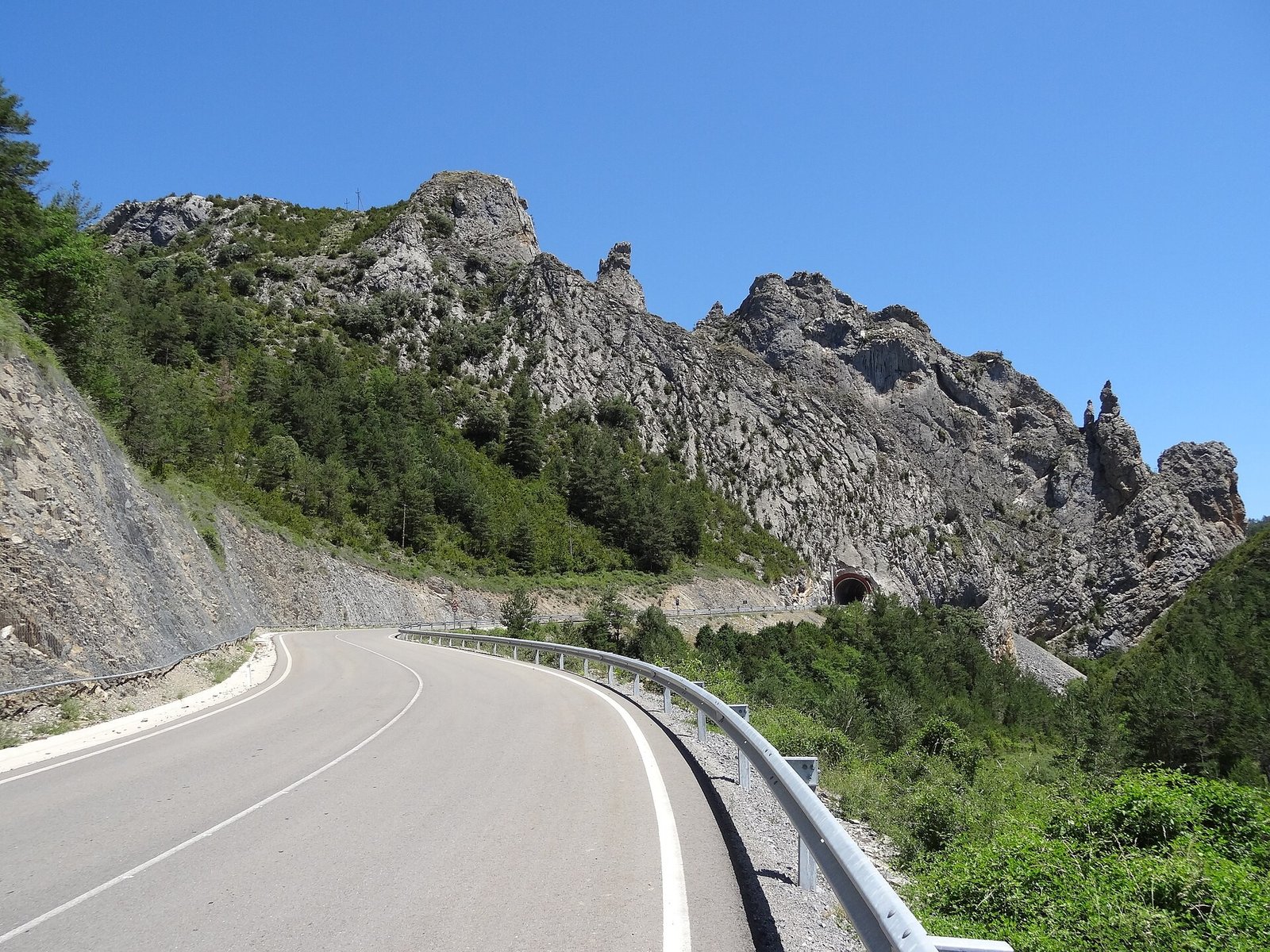 Carretera de montaña estrecha con curvas junto a una pared de roca