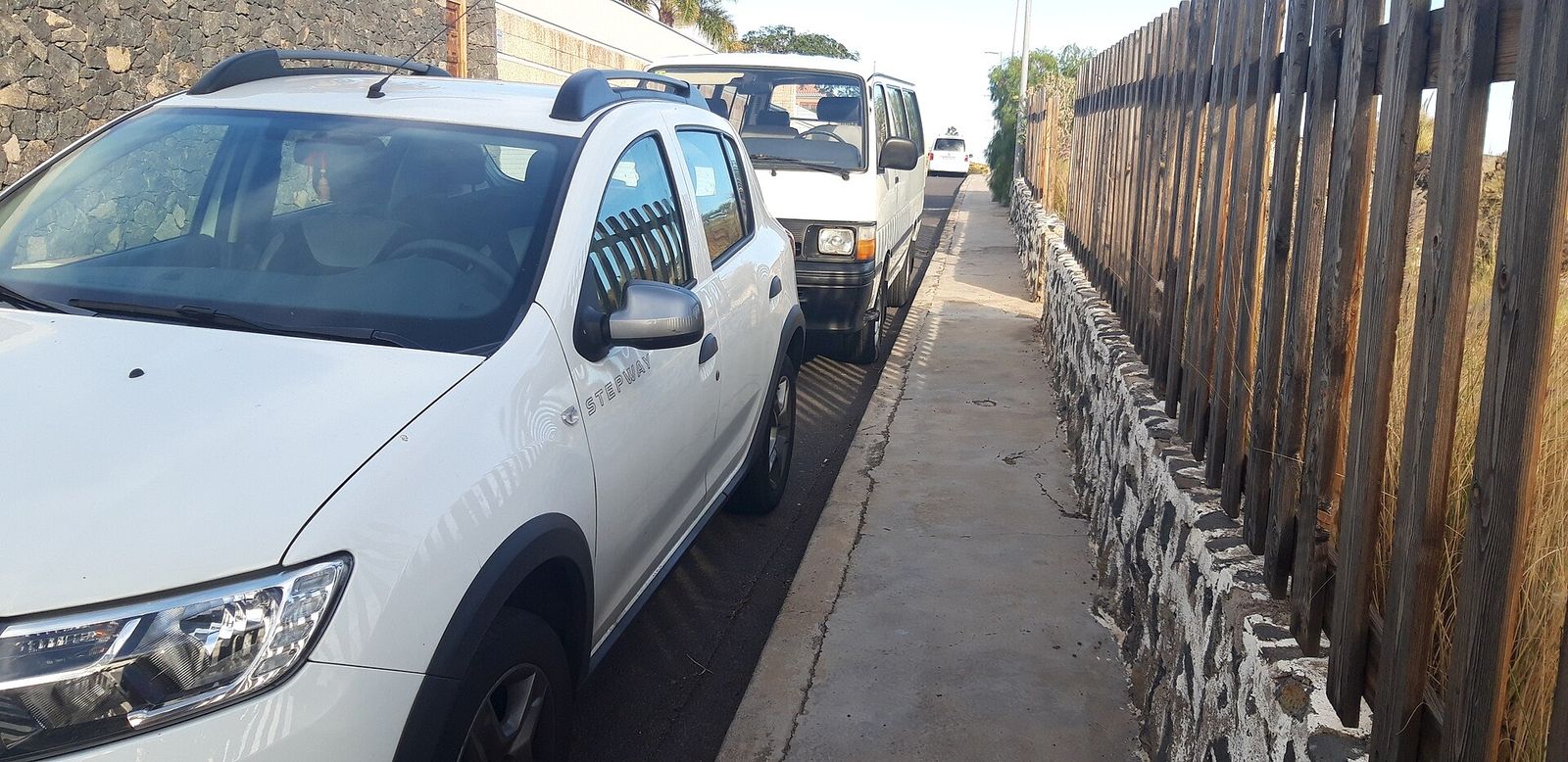 Calle estrecha con coches aparcados que dejan poco espacio para circular