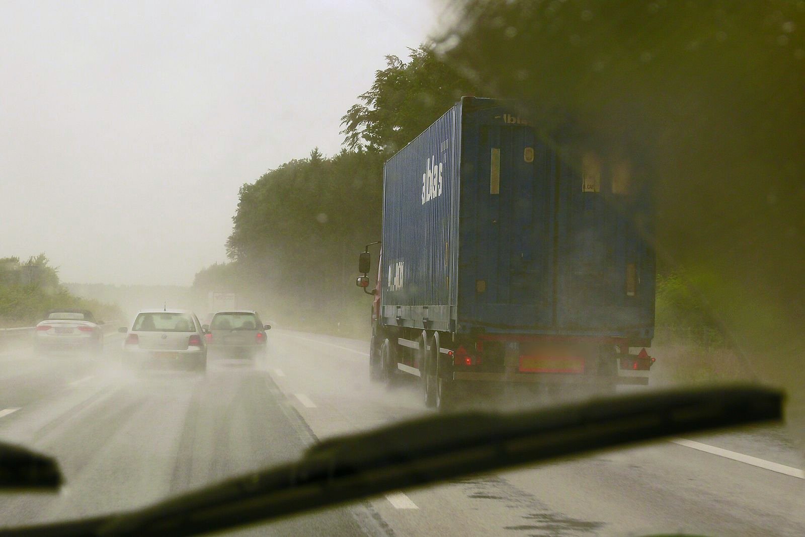 Autopista bajo lluvia intensa vista desde el parabrisas, con un camión por delante